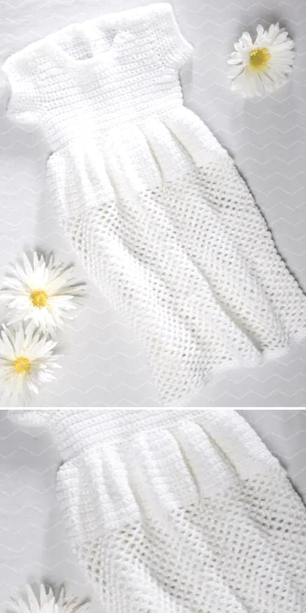 crocheted baby dress in white color laid next to three daisy flowers