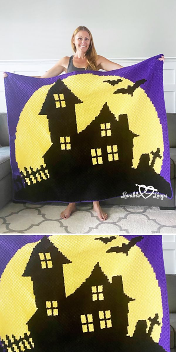 A woman is displaying a crocheted Halloween house blanket.