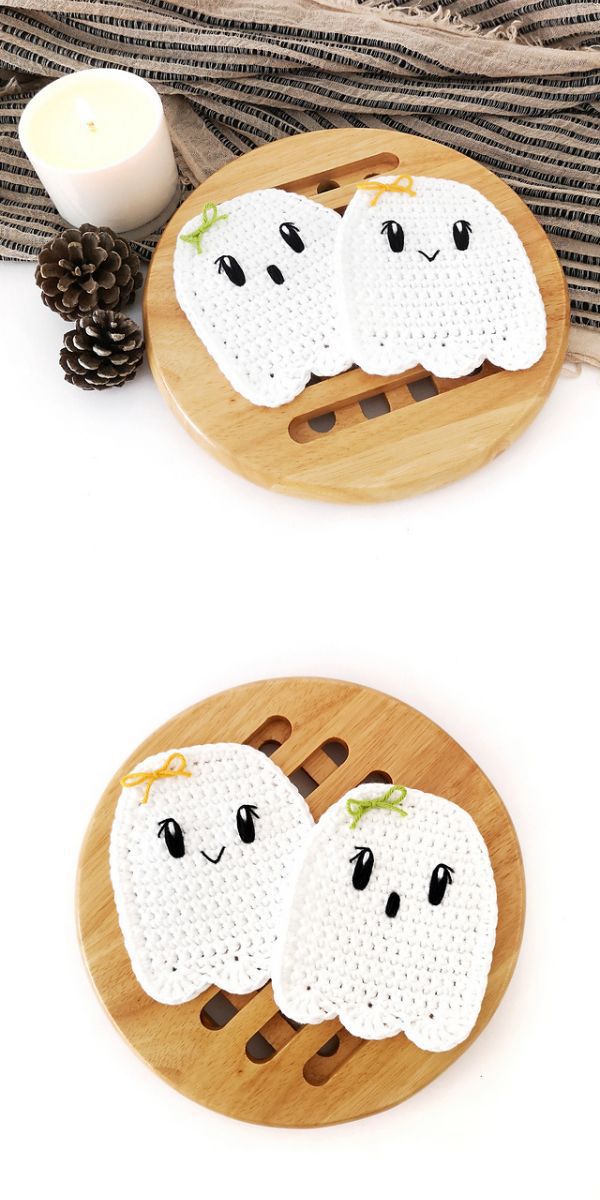 Two crocheted Halloween ghosts on a wooden plate.