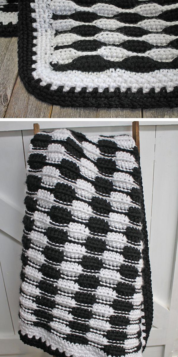 A black and white wavy crocheted throw hanging on a hook.