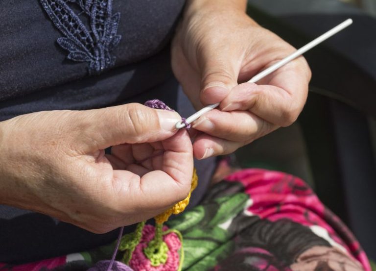 Close-up of a person's hands crocheting a chain stitch with a hook and colorful yarn.