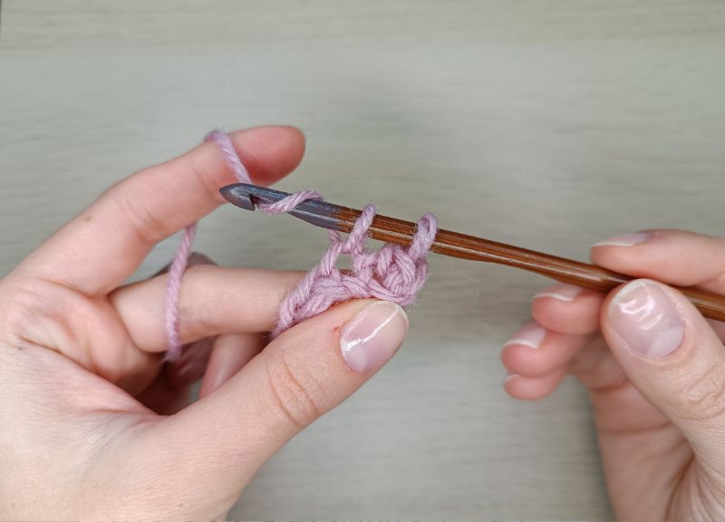 woman's hands with a crochet hook in the right one showing how to single crochet