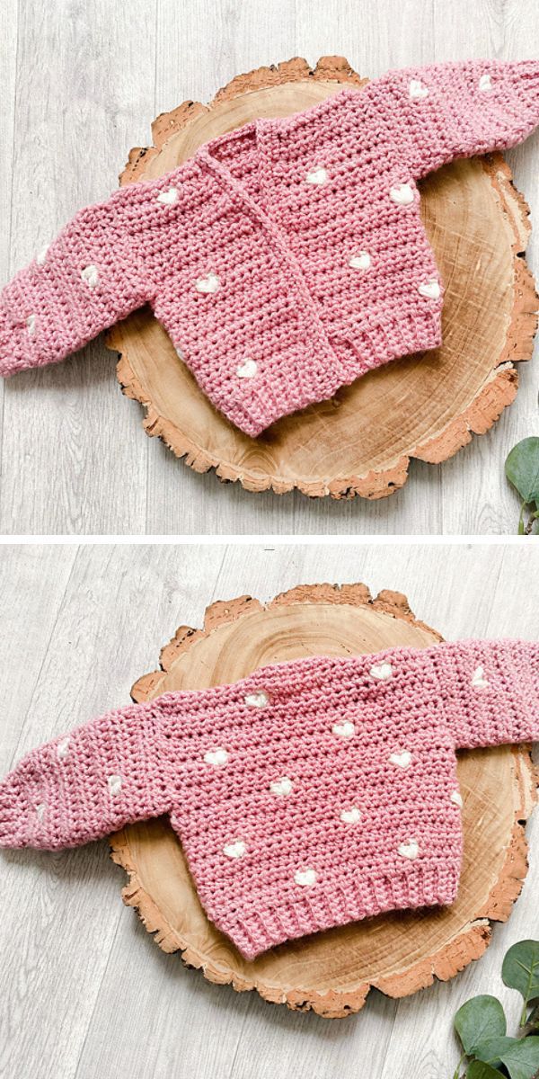 a crochet baby cardigan in pink color and heart motifs laid on a wooden piece