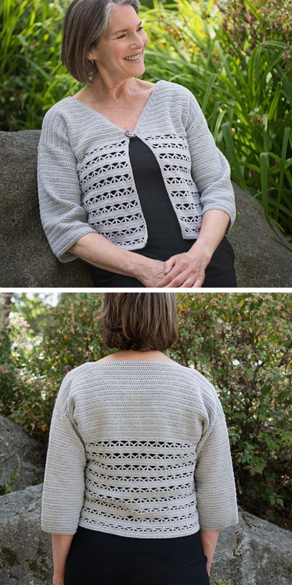 A woman wearing a grey, crochet cardigan with lace detailing sits outdoors on a large rock. 