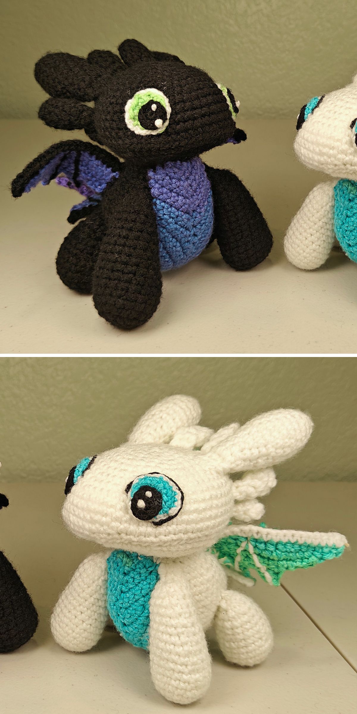 Two crochet dragons, one black with purple and blue accents, the other white with blue and green accents, are displayed on a light surface.