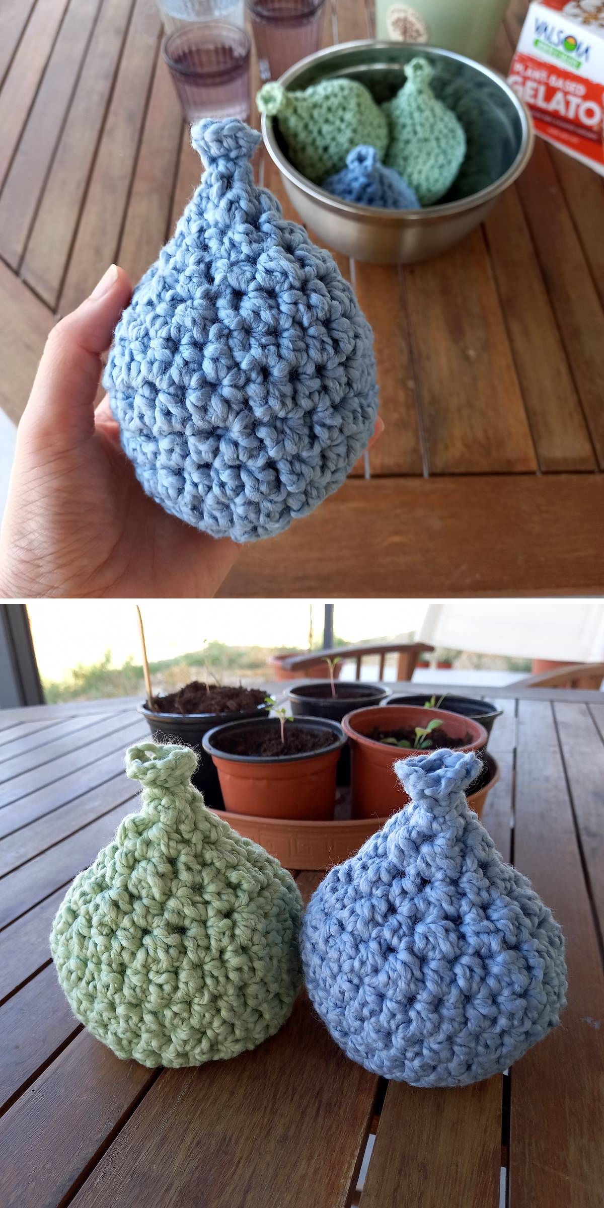 Crochet baby toys shaped like pears in blue and green are displayed on a wooden table, with some nestled in a bowl and others arranged in front of potted plants.