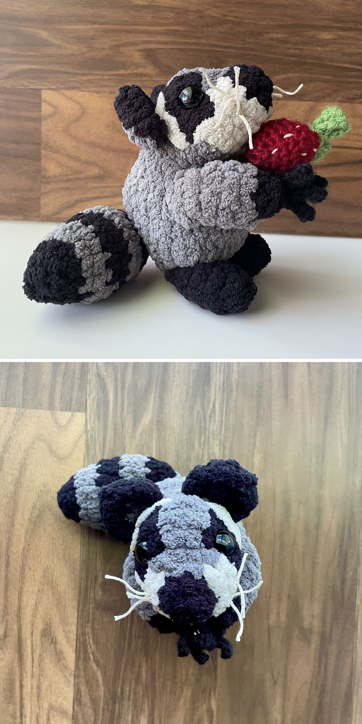 A crochet raccoon plush toy holding a red strawberry, shown from a side view on a wood background and from above on a lighter wood surface.
