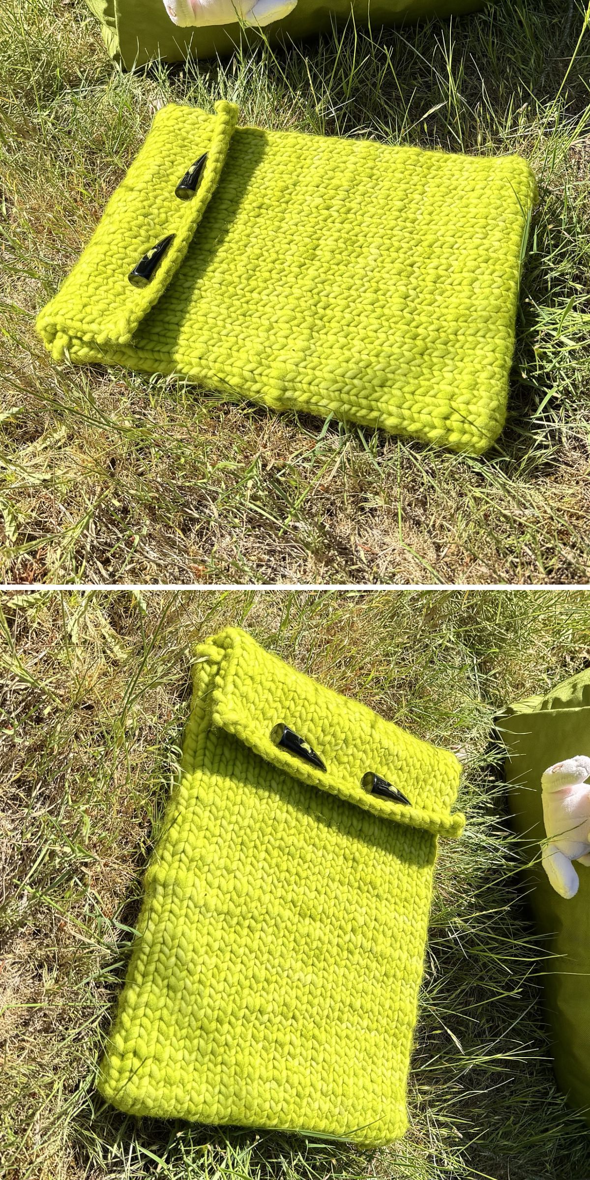 A handmade, bright green knitted sleeve — perfect for small projects — with two black toggle buttons, lying on grass in the sunlight.
