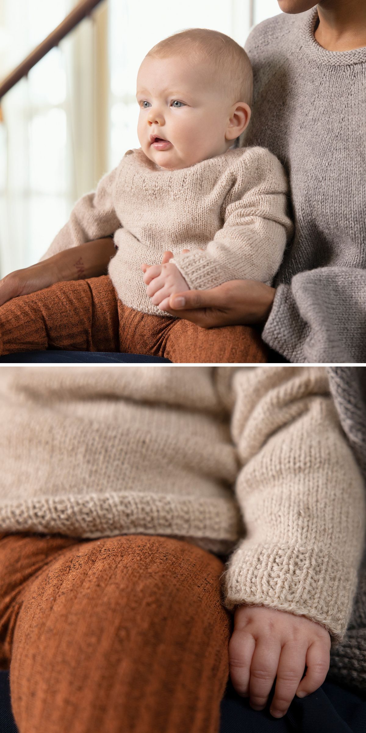 A baby in cozy knitted kids clothes — beige sweater and brown pants — sits on an adult's lap, gently holding their hand in a softly lit indoor setting.