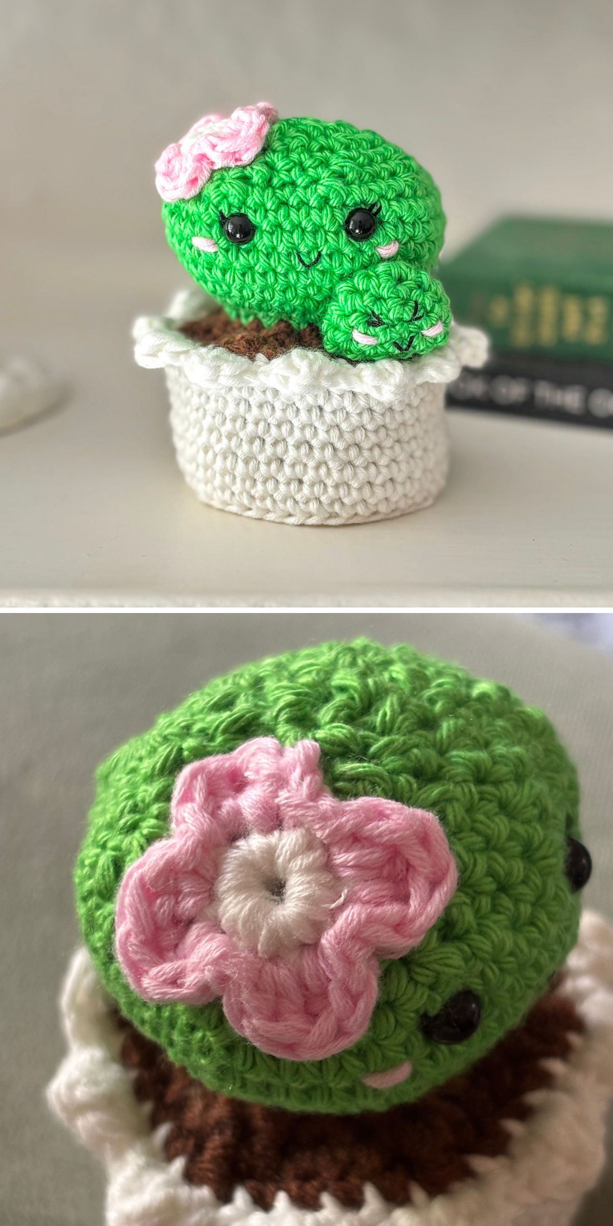A crochet plant, this green cactus with a pink and white flower sits in a white crochet pot. The cactus has black eyes and a small smile. Close-up highlights the detailed flower on this charming crochet creation.