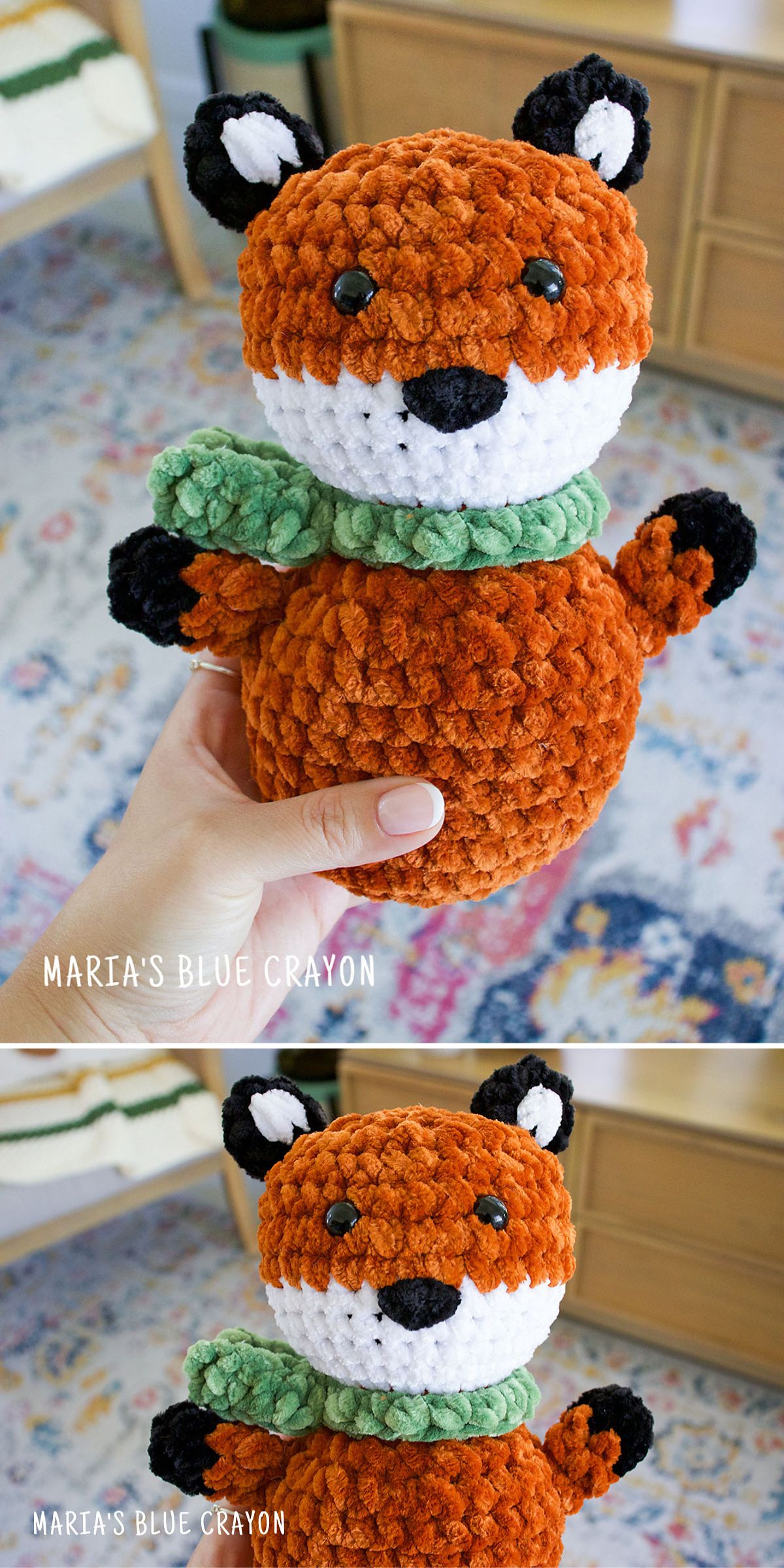 A hand holds a crochet fox plushie with a green scarf and black-tipped ears, shown up close and resting on a patterned rug.