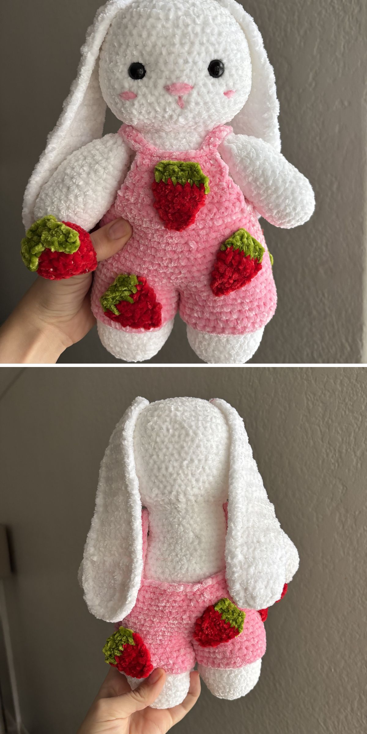 A plush white crochet bunny toy with long ears, wearing pink overalls decorated with red and green strawberry patches, shown from the front and back.