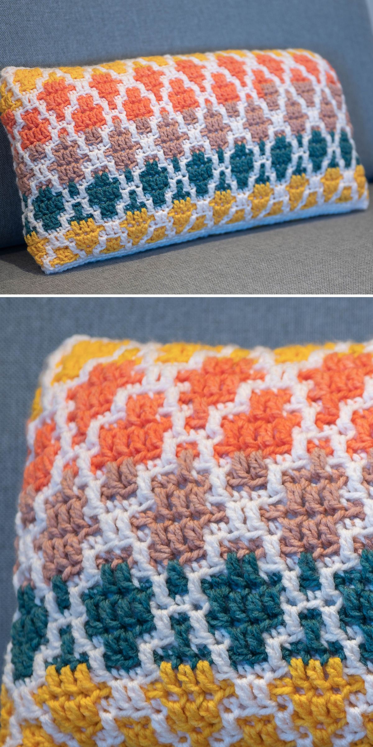 A crochet pillow with a rectangular shape and geometric pattern in orange, yellow, teal, beige, and white rests on a gray upholstered surface.