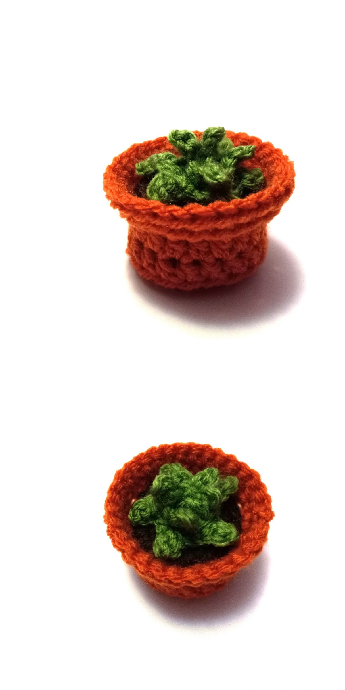 A small crochet plant with green leaves sits in an orange pot, displayed from a side view and a top view on a white background.