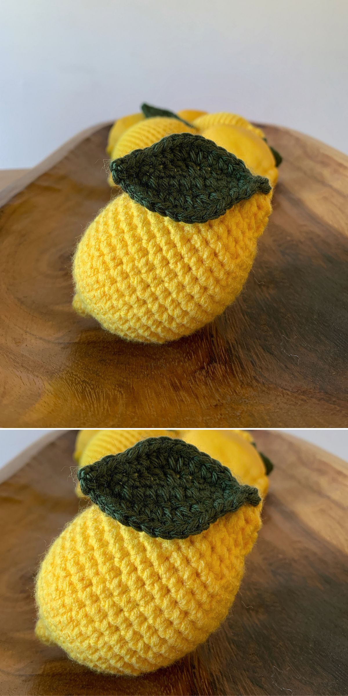 Two crochet lemons with green leaves rest on a wooden surface, adding a touch of handmade charm.
