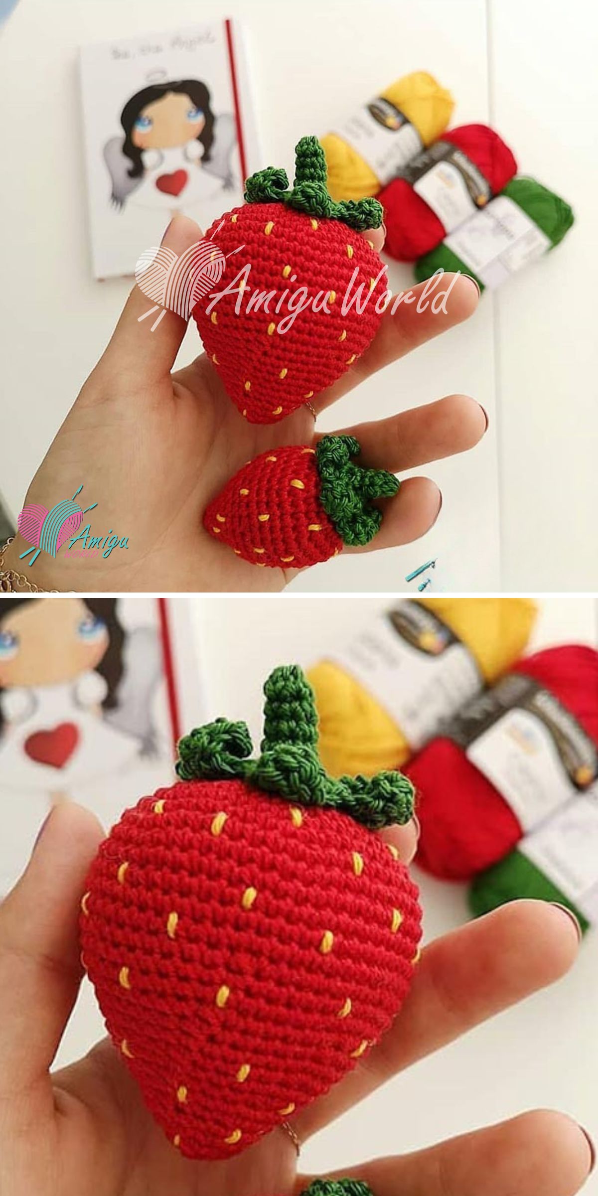 Two handmade crochet strawberries, one large and one small, are held in a hand with colorful yarn and a book in the blurred background.