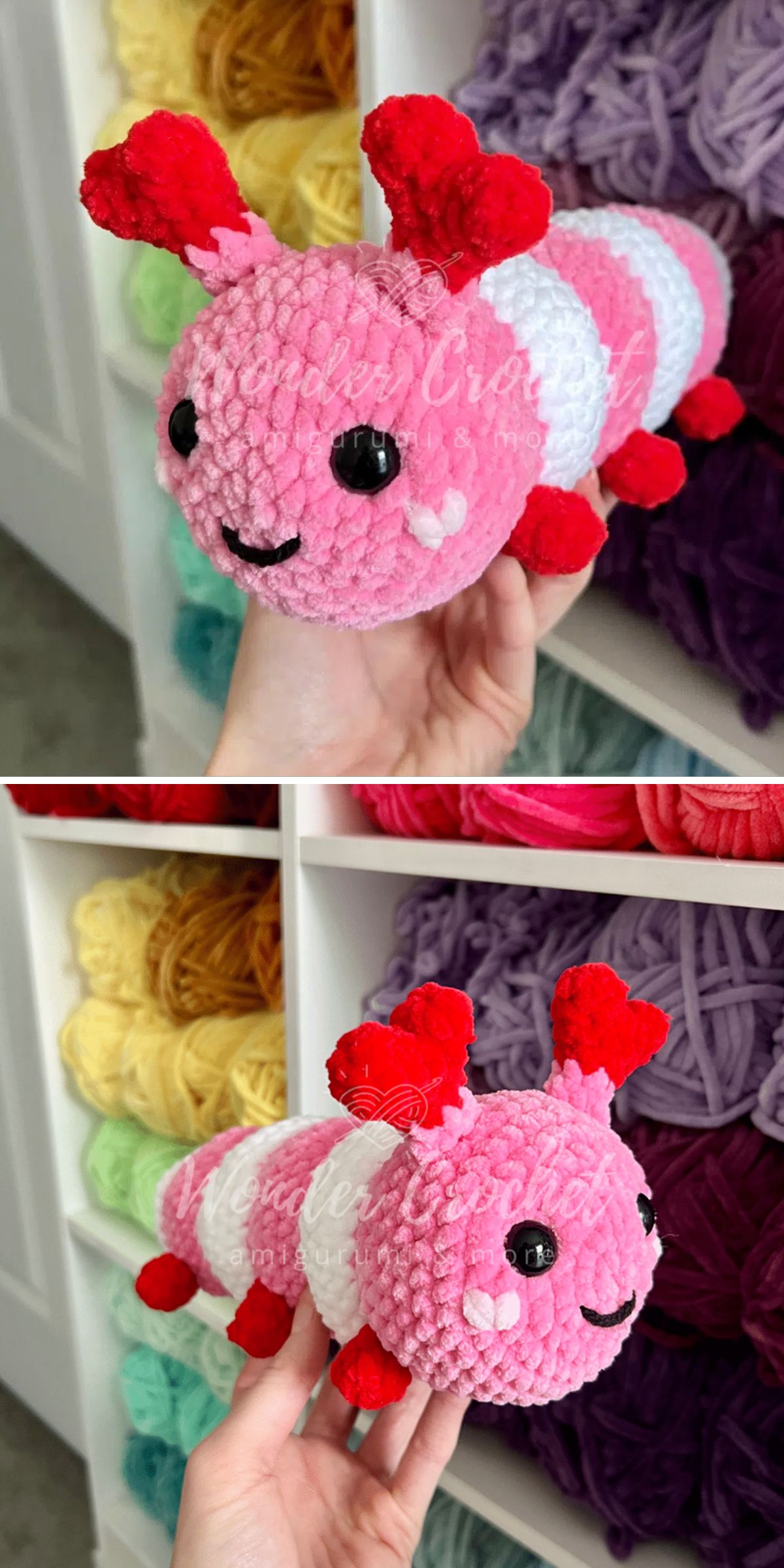 A hand holds a pink and white crochet insect plushie shaped like a caterpillar, with red antennae, black eyes, and a smiling face. Yarn skeins in various colors are visible on shelves in the background.