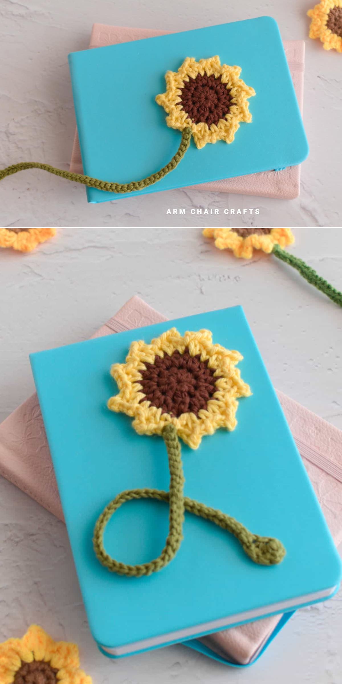 A blue notebook with a crochet sunflower and green stem bookmark rests atop a pink book on a light surface.