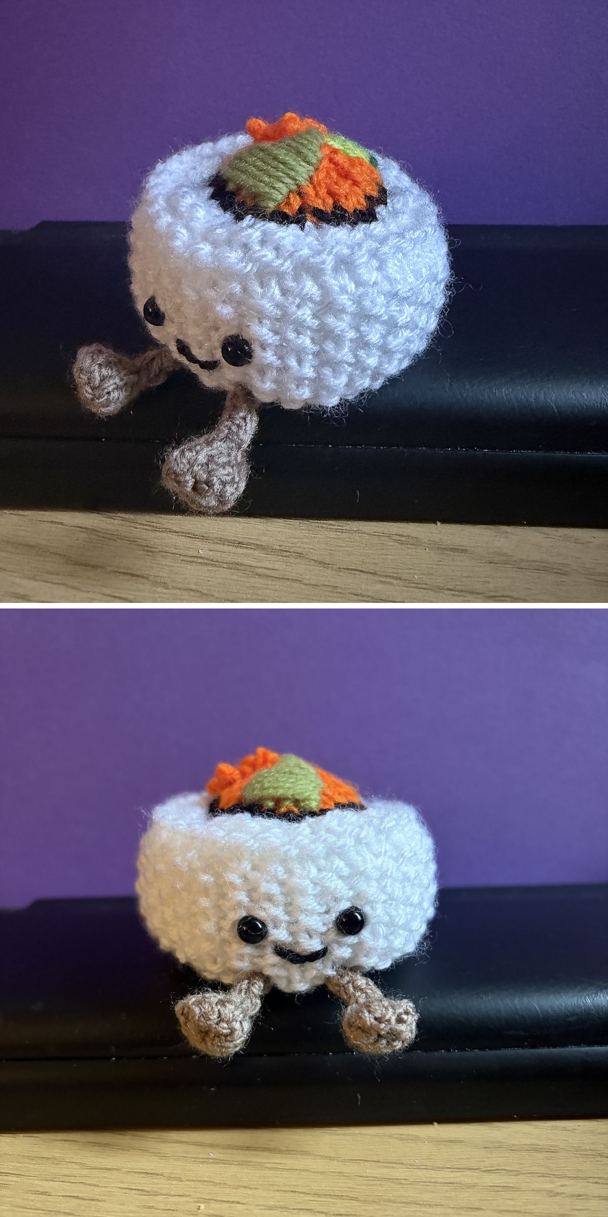 A knitted sushi roll plush with a smiling face, brown feet, and colorful orange and green topping sits on a black surface against a purple background—an adorable addition for fans of Knitted Food Patterns.