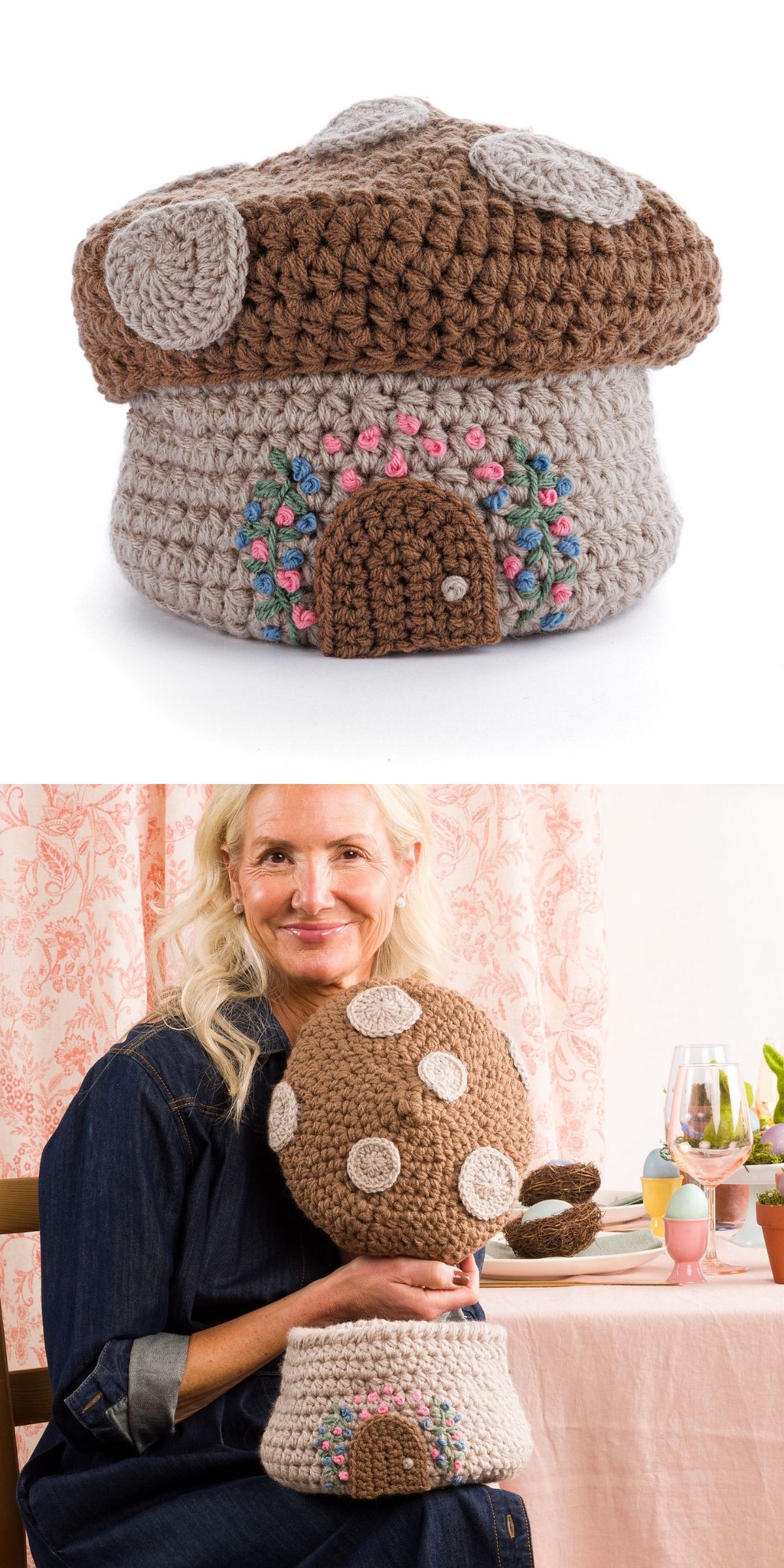 A woman holds a crochet basket shaped like a brown mushroom house with a decorated door and white spots, while seated at a table, beautifully showcasing her skills in Mushroom Crochet.