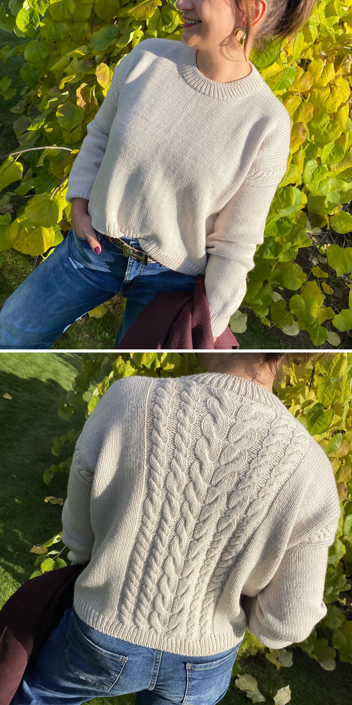 Woman wearing a cream knit sweater with a plain front and an intricate cable-knit pattern on the back, paired with blue jeans, standing outdoors near green foliage. This classic knit sweater adds warmth and timeless style to her casual look.