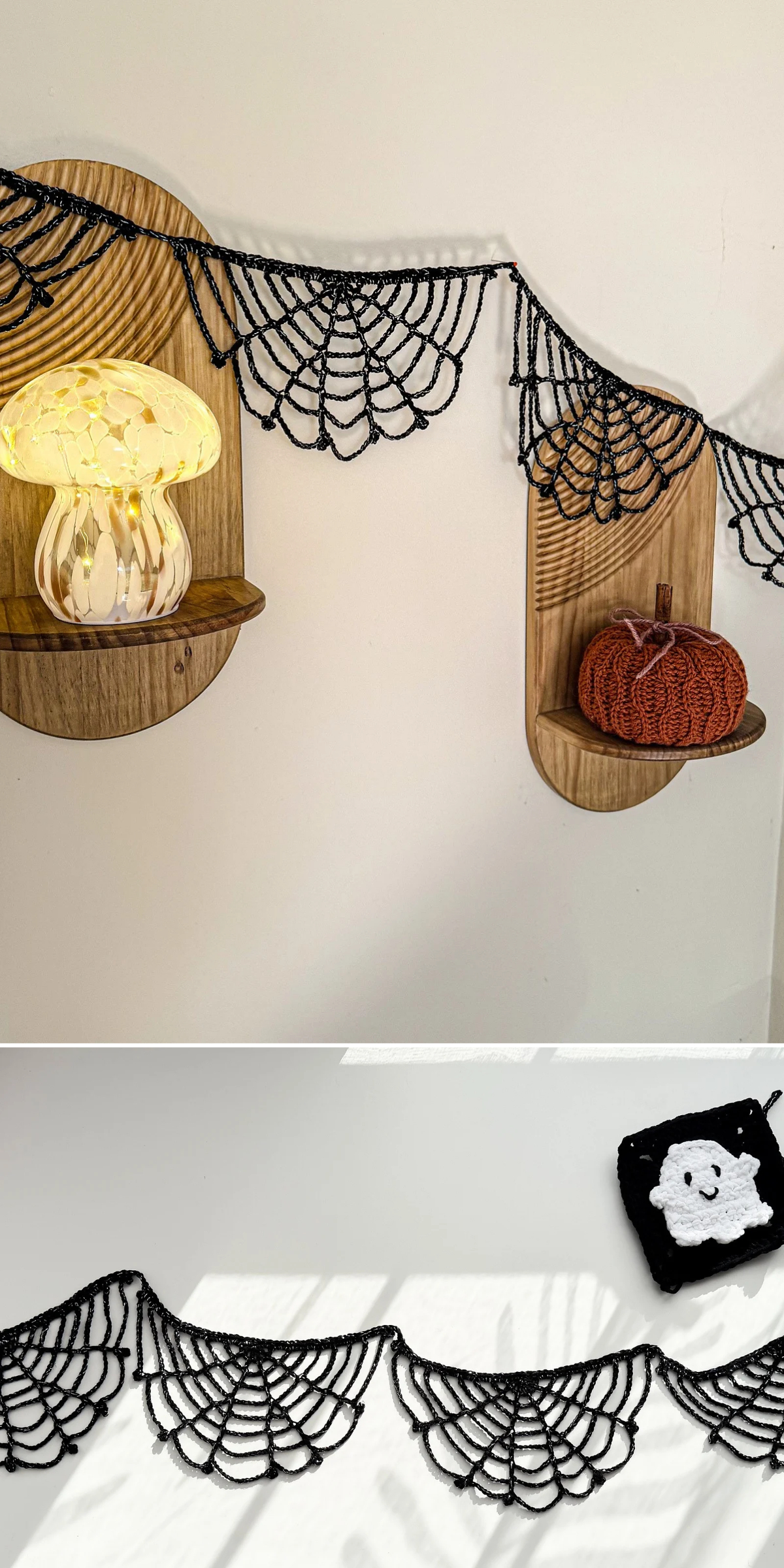 A crocheted black spiderweb garland drapes across a white wall between two shelves holding a glowing glass mushroom lamp, a crocheted orange pumpkin, and a ghost coaster in this crochet halloween applique.